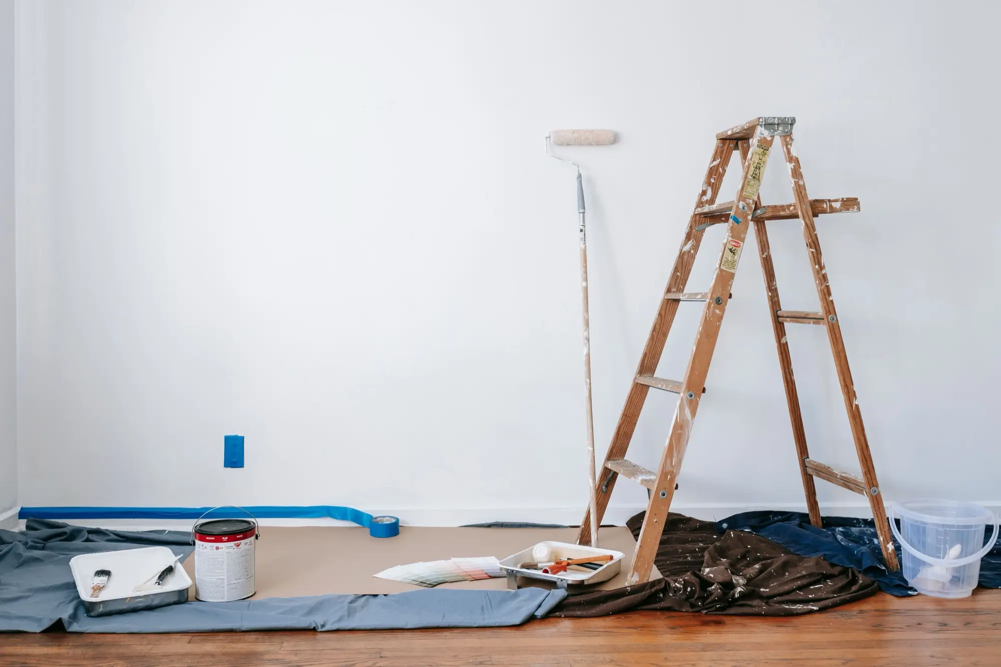 Room prepared for painting with drop sheets, ladder and colour swatches